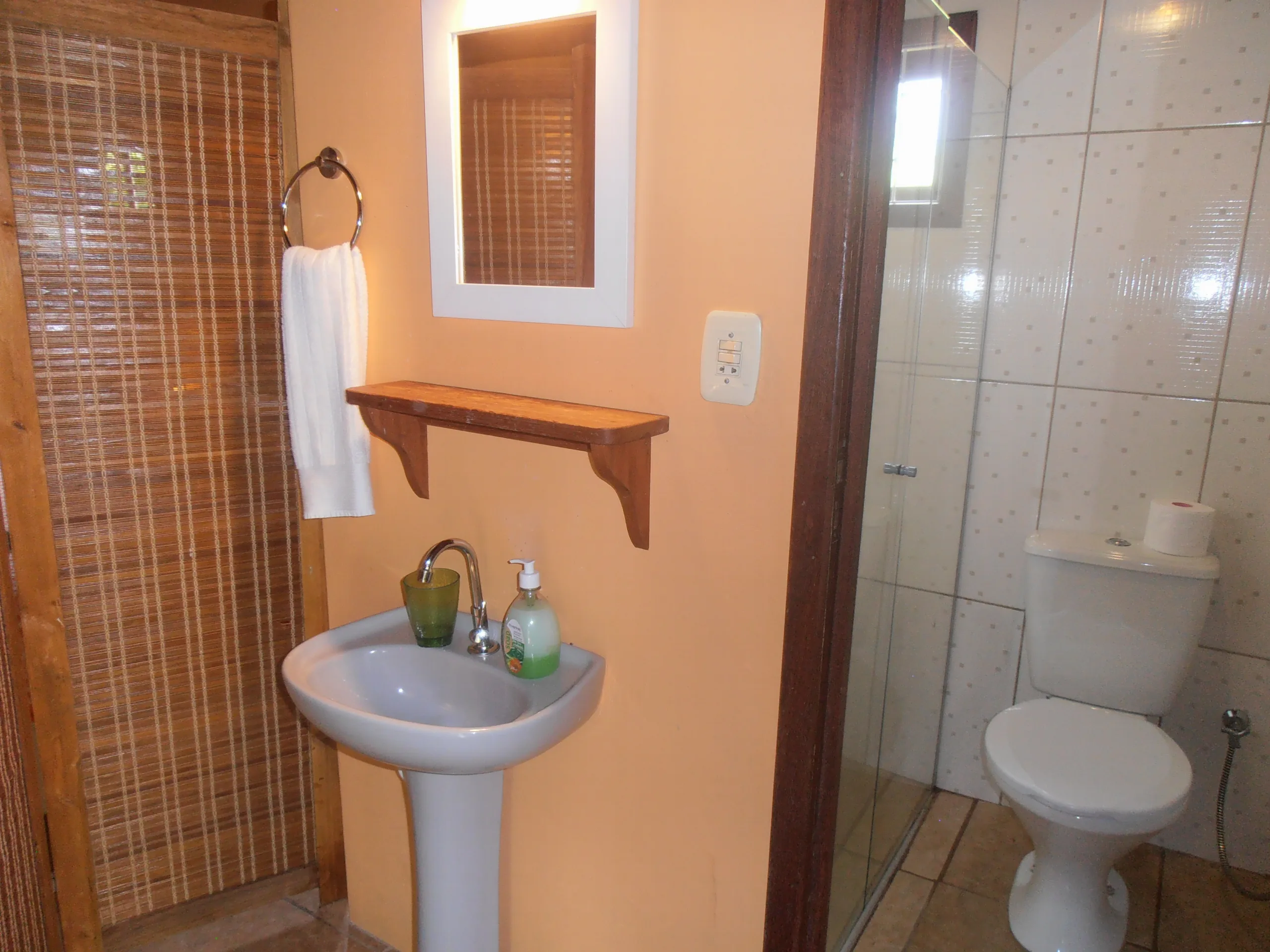 Banheiro privativo do Bungalow 11 com box de vidro e chuveiro quente