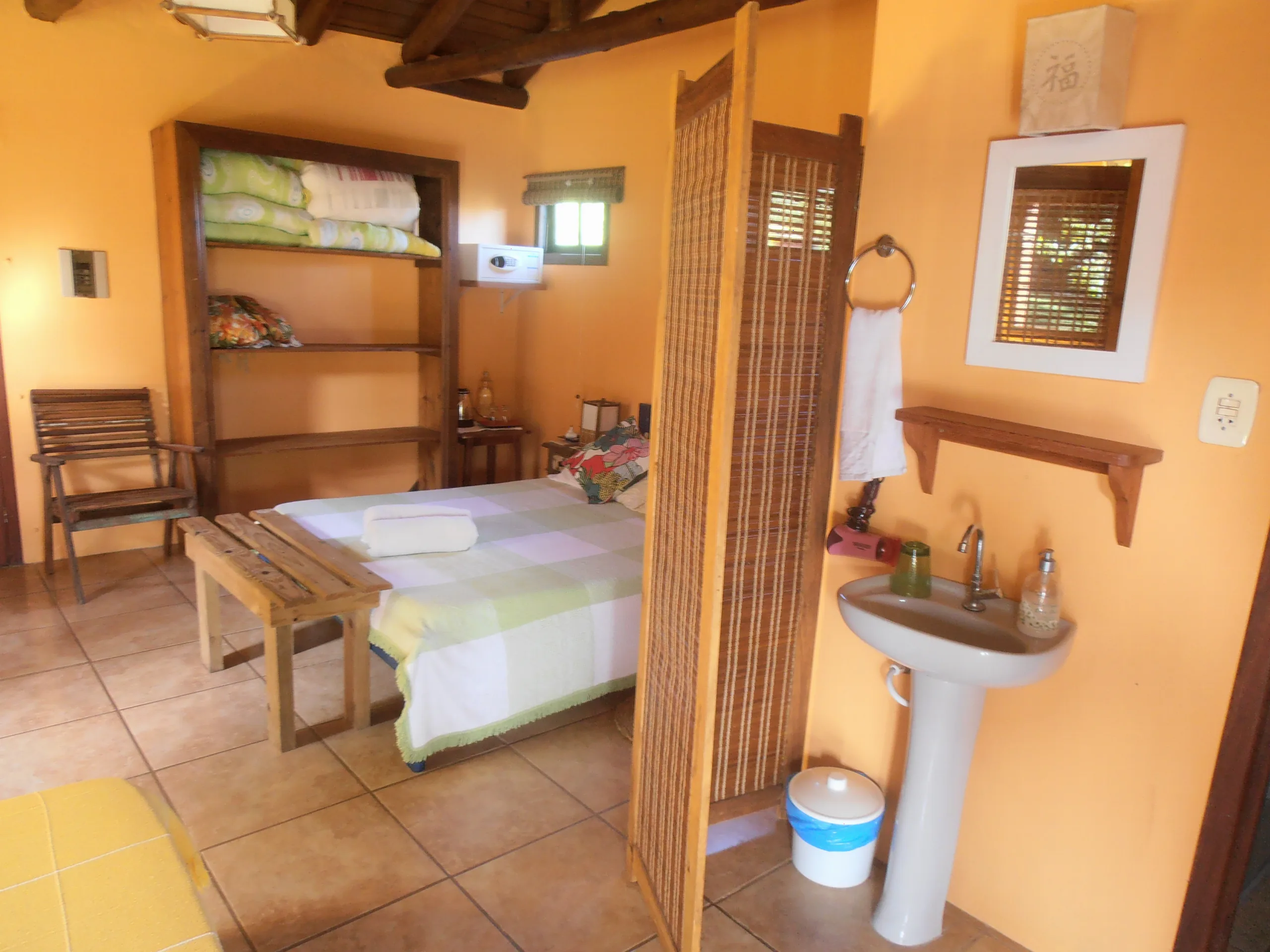 Interior do Bungalow 11 com teto de madeira, biombo de bambu e pia