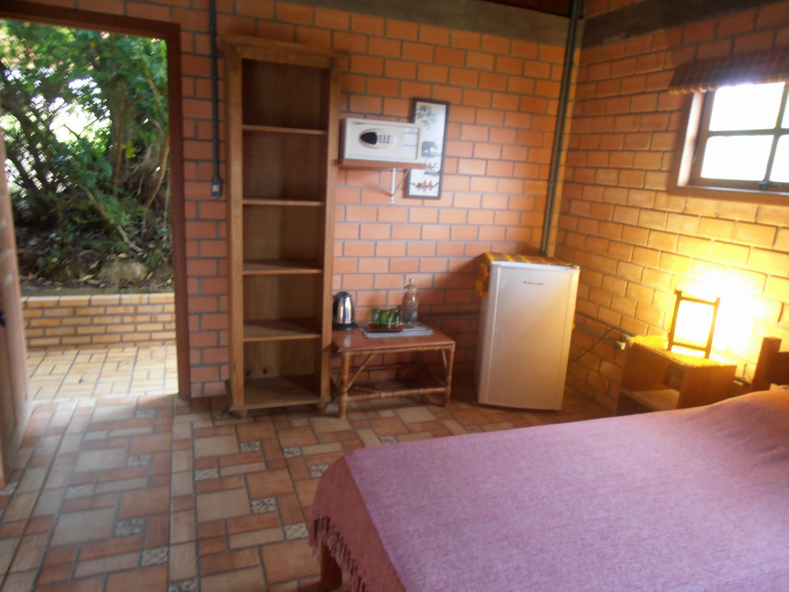 Frigobar, chaleira e estante do Bungalow 12, com saída para o jardim