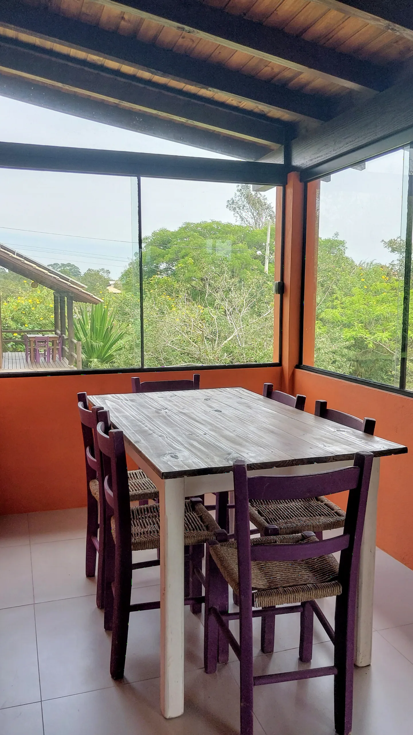 Varanda coberta do Bungalow 12 com mesa para seis pessoas e vista para o verde