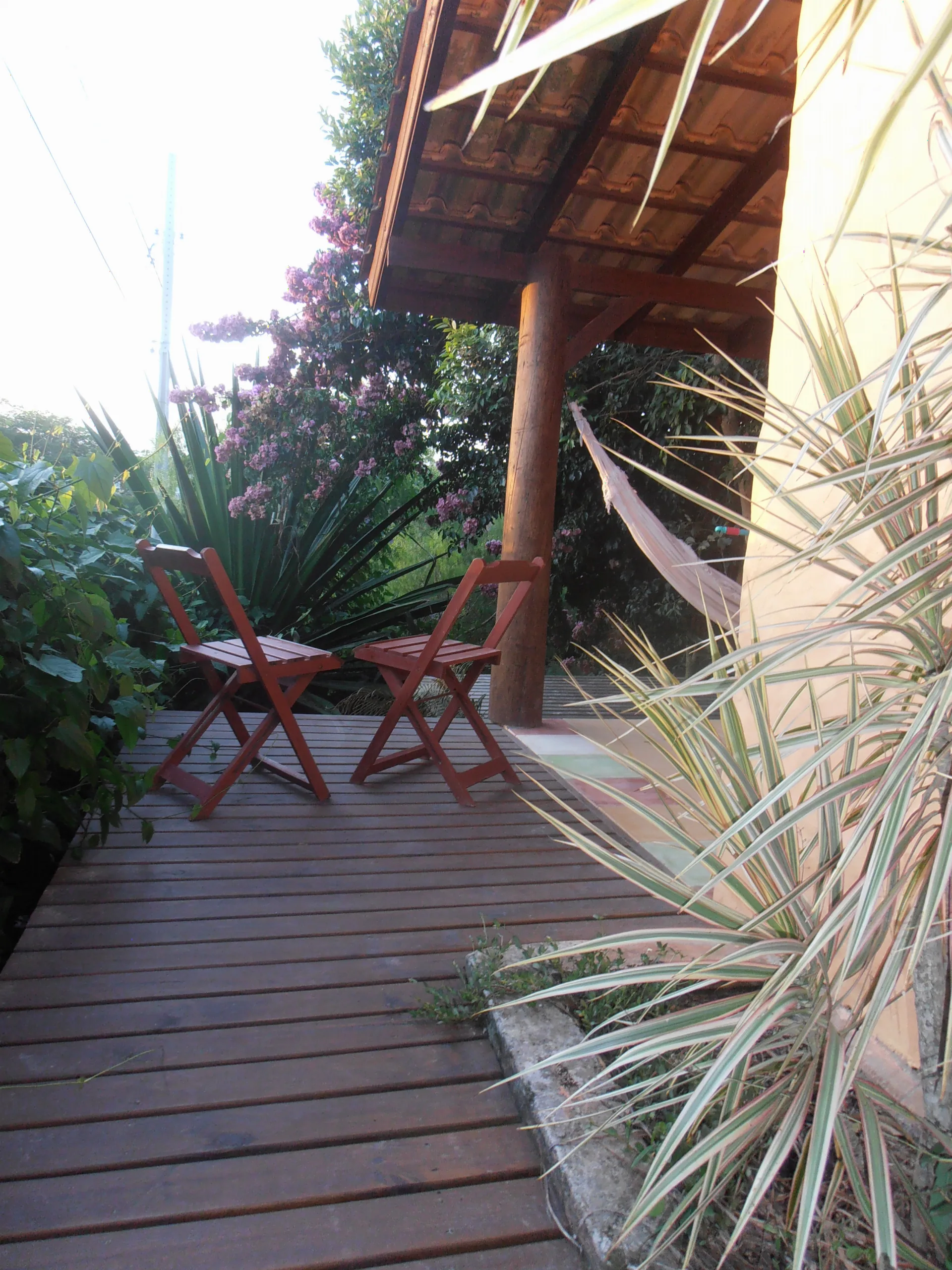 Deck de madeira da Suíte 10 com cadeiras à sombra do jardim