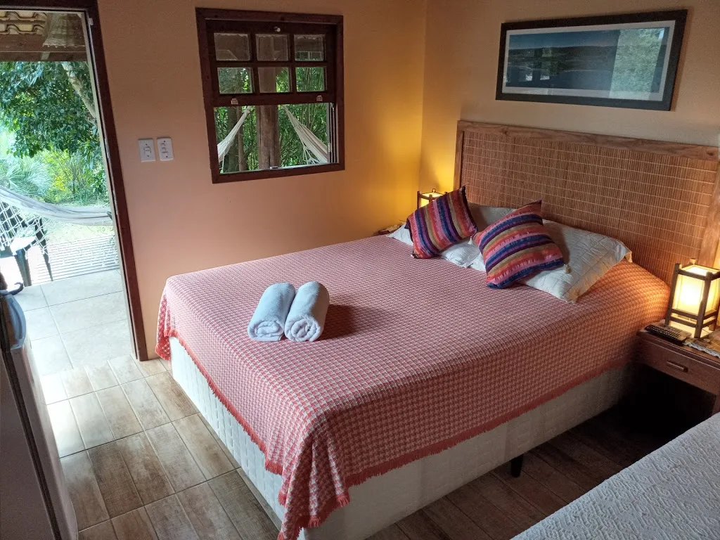 Suíte 10 com cama de casal e porta aberta para a varanda com rede