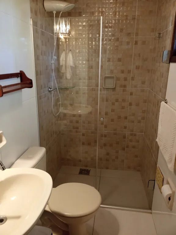 Banheiro da suíte com box revestido de pastilhas e chuveiro quente