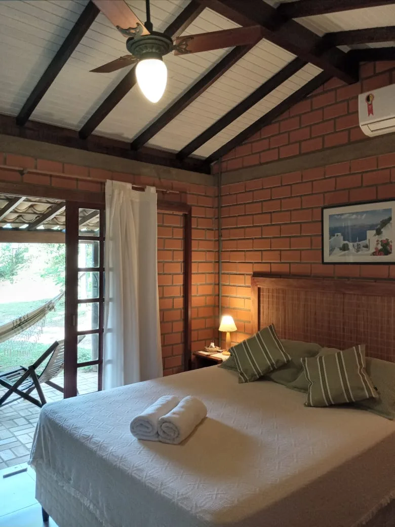 Suíte com ventilador de teto, ar-condicionado e porta para a varanda com rede