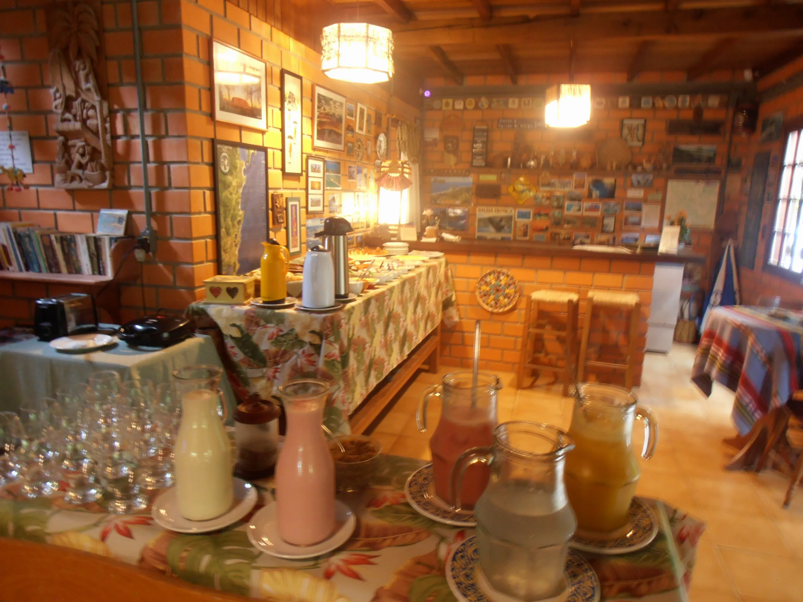 Buffet do café da manhã colonial com sucos, leite e frios no salão da pousada