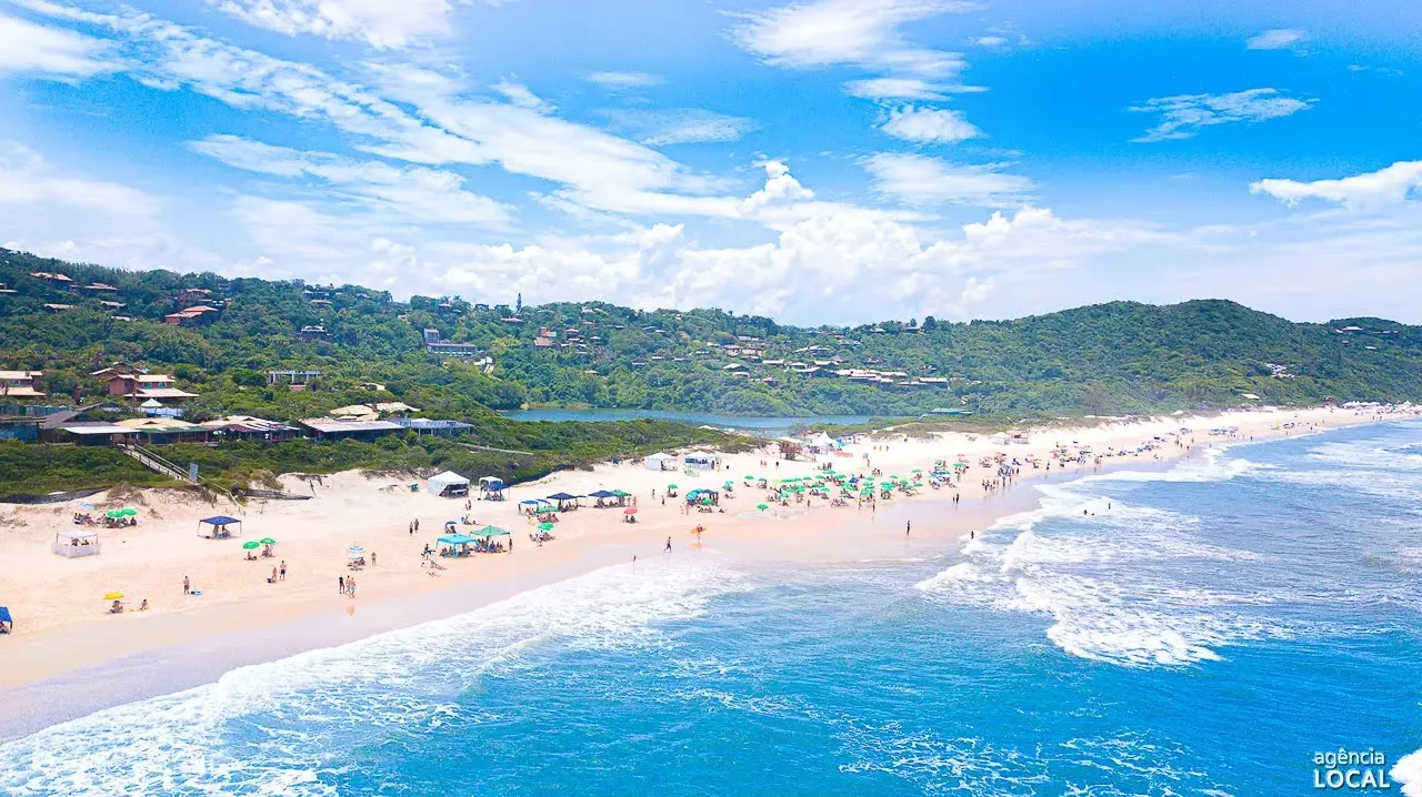 Praia do Rosa cheia no verão com guarda-sóis coloridos